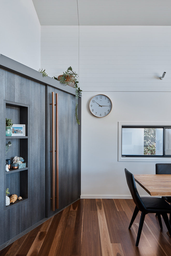 Diseño de comedor costero pequeño abierto con paredes blancas, suelo de madera en tonos medios y suelo marrón
