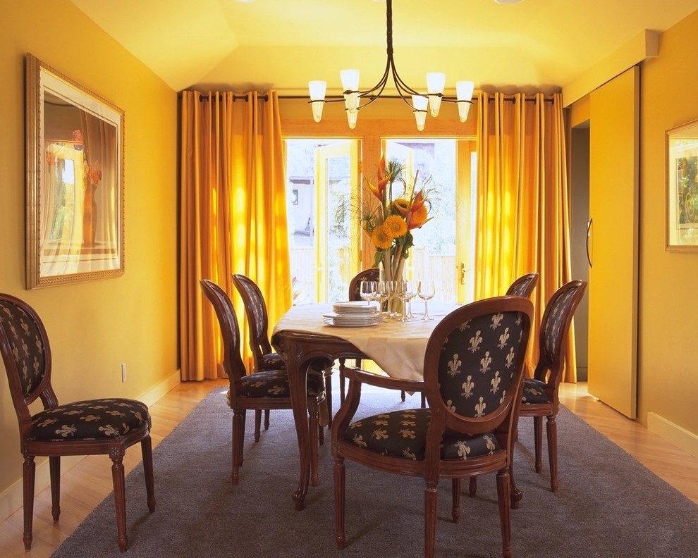 На фото: столовая в современном стиле с желтыми стенами и паркетным полом среднего тона с