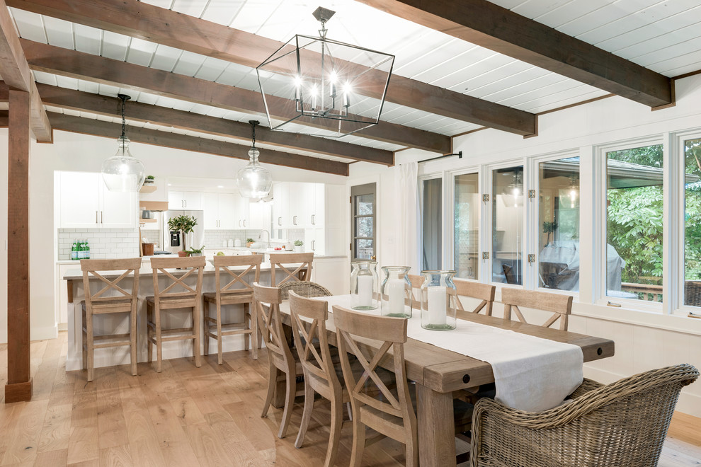 Cette photo montre une salle à manger ouverte sur la cuisine montagne de taille moyenne avec un mur blanc, parquet clair et un sol beige.