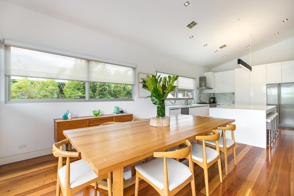 Ispirazione per una sala da pranzo aperta verso la cucina minimal di medie dimensioni con pareti bianche e pavimento in legno massello medio
