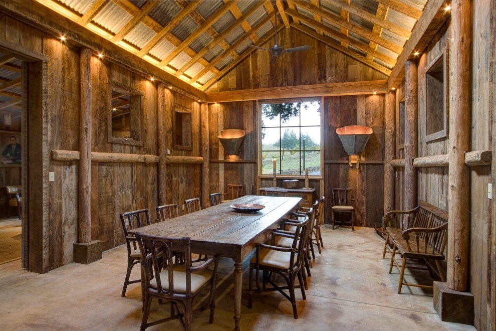 Idee per una grande sala da pranzo stile rurale chiusa con pareti marroni, pavimento in cemento, nessun camino e pavimento grigio
