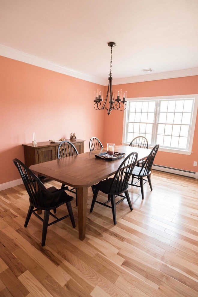Geschlossenes Landhausstil Esszimmer mit oranger Wandfarbe und hellem Holzboden in New York