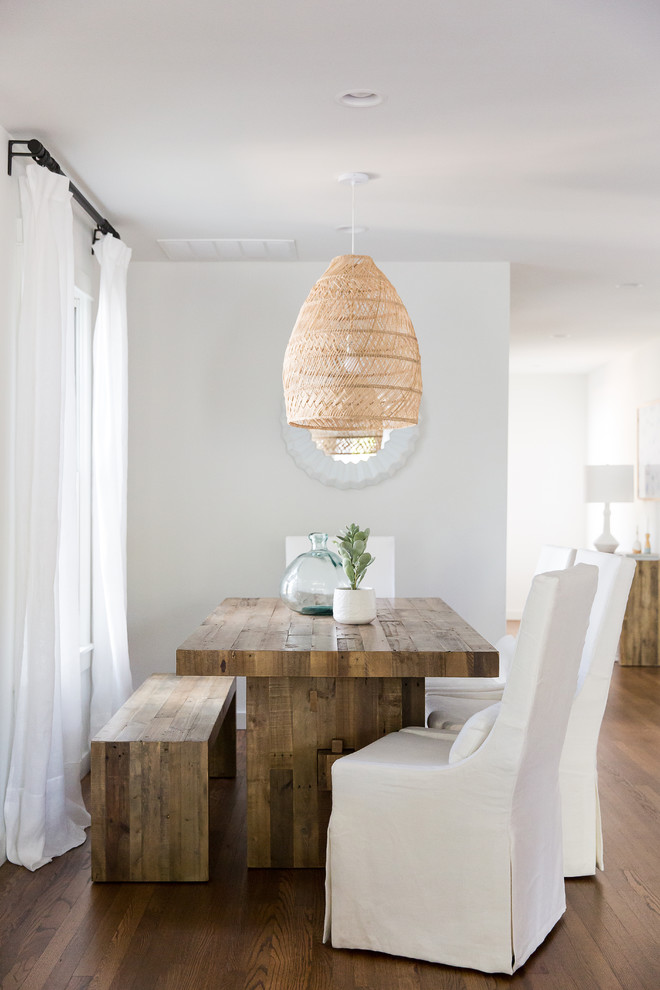 Beach style dining room in New Orleans with white walls, dark hardwood flooring, brown floors and feature lighting.