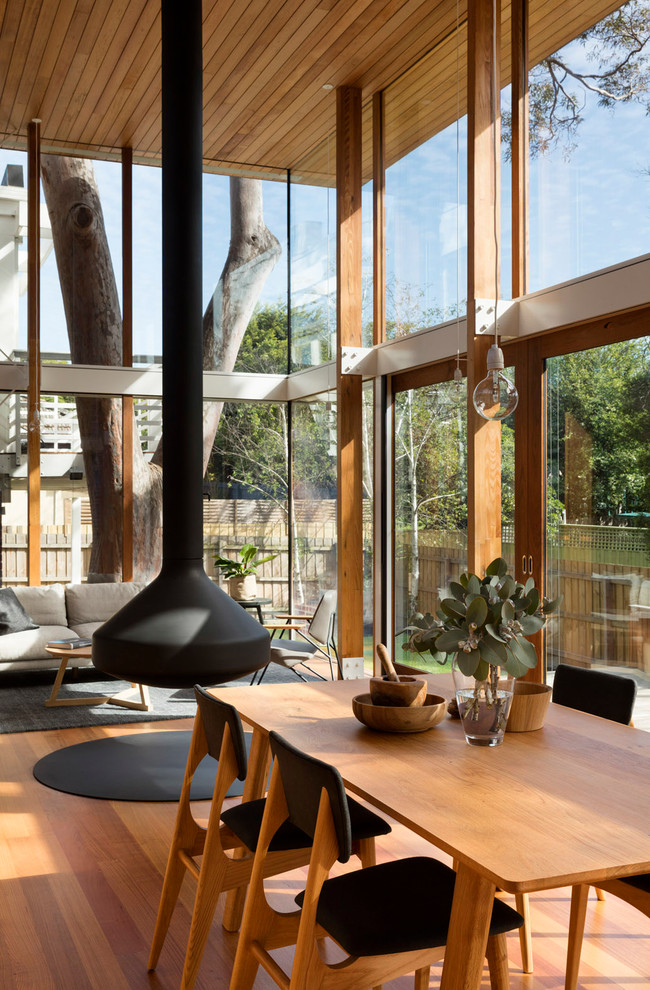 Cette image montre une salle à manger ouverte sur le salon design avec un sol en bois brun et un sol orange.