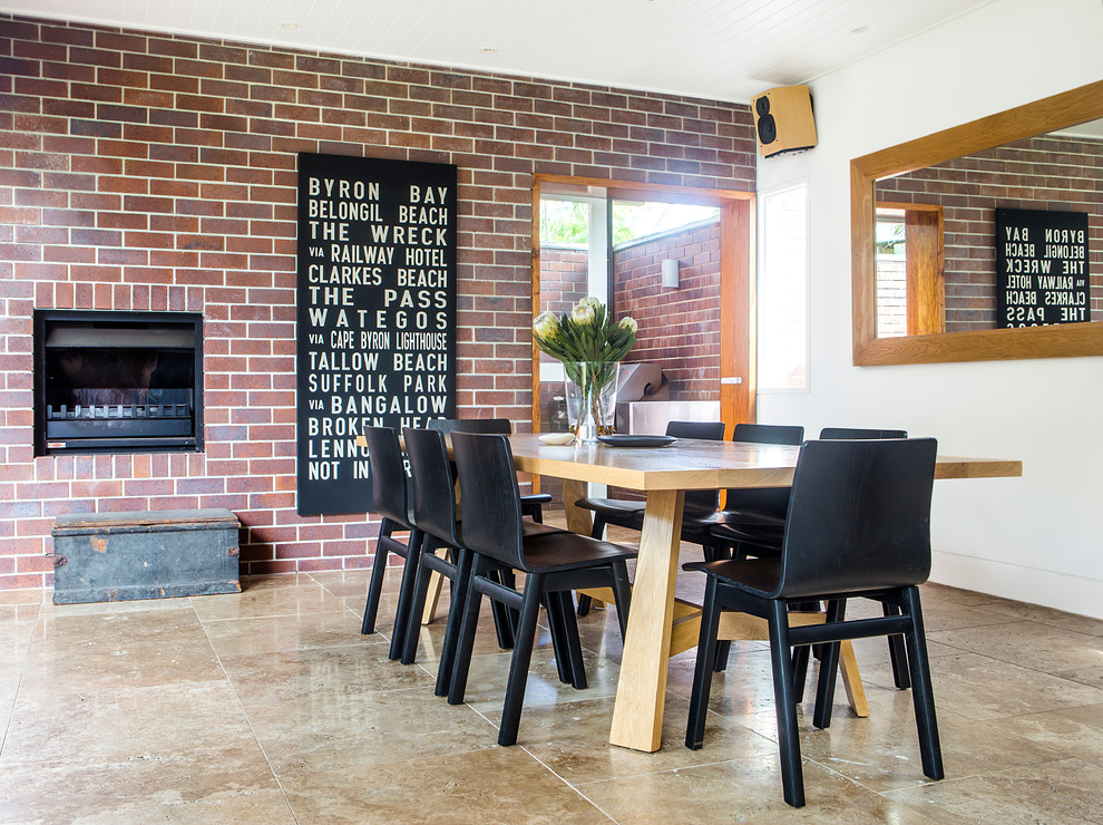 Cette photo montre une salle à manger tendance avec un mur rouge et un manteau de cheminée en brique.