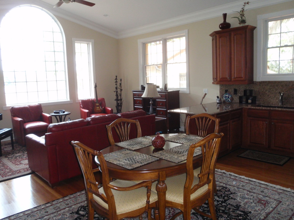 Cette image montre une salle à manger ouverte sur le salon traditionnelle de taille moyenne avec un mur beige, un sol en bois brun et un sol marron.