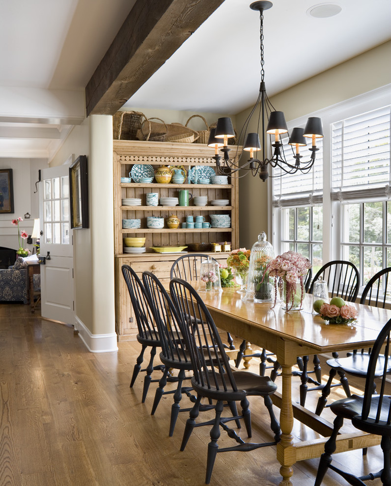 Cette photo montre une salle à manger ouverte sur la cuisine chic de taille moyenne avec un mur beige, un sol en bois brun et aucune cheminée.