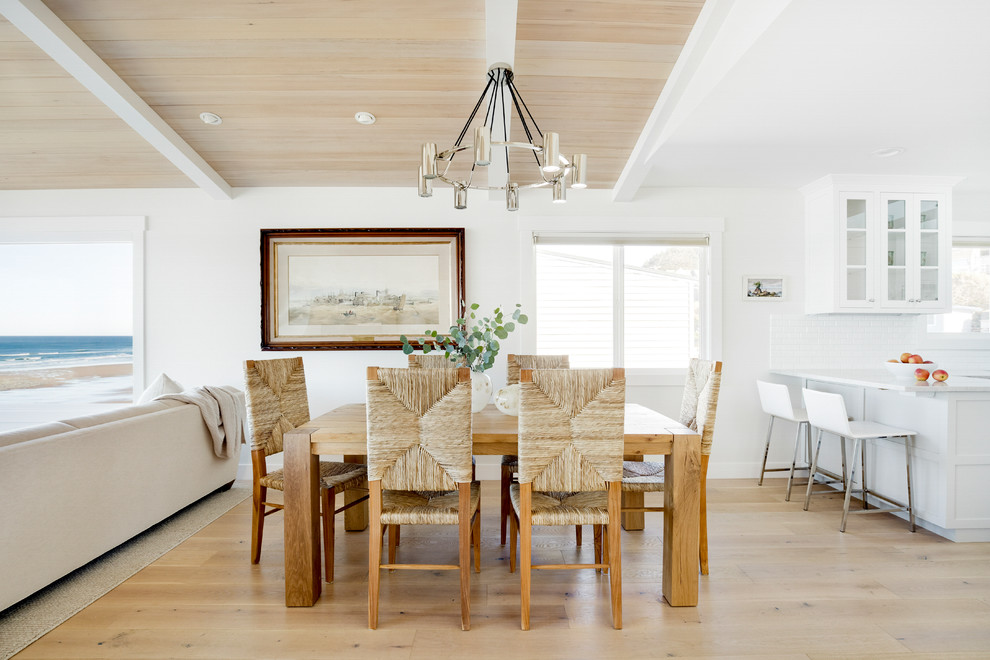 Immagine di una sala da pranzo aperta verso il soggiorno stile marino con pareti bianche, parquet chiaro e pavimento beige