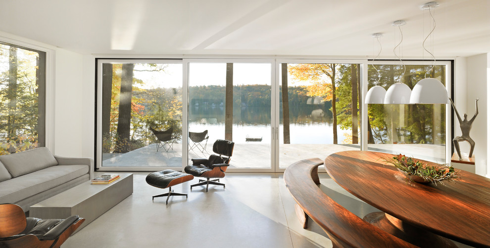 Idée de décoration pour une grande salle à manger ouverte sur le salon design avec un mur blanc, sol en béton ciré et un sol gris.