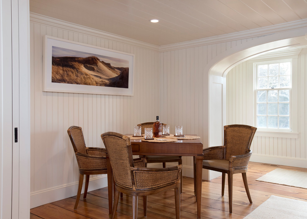 Example of a beach style medium tone wood floor and brown floor dining room design in Boston with white walls