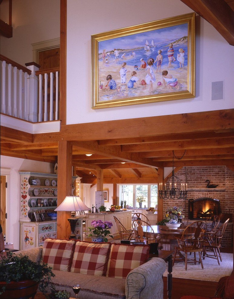 Exemple d'une salle à manger ouverte sur le salon craftsman avec un mur blanc, un sol en bois brun, une cheminée standard et un manteau de cheminée en brique.