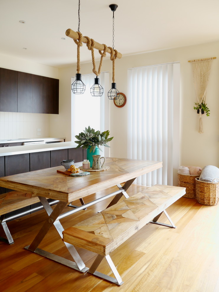 Immagine di una sala da pranzo aperta verso la cucina stile marinaro di medie dimensioni con pareti bianche, pavimento in legno massello medio e pavimento marrone