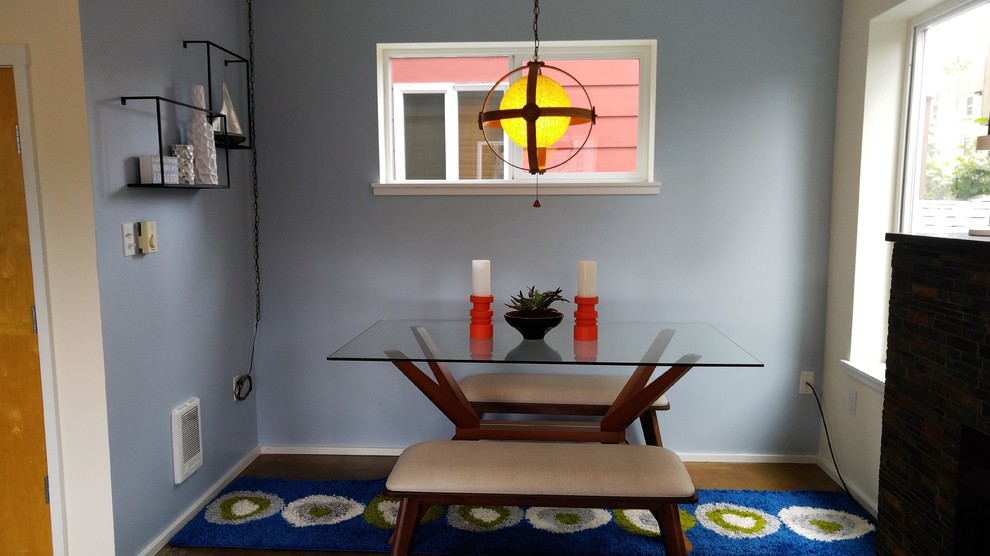 Foto di una piccola sala da pranzo aperta verso il soggiorno moderna con pareti blu, pavimento in cemento, camino classico e cornice del camino in pietra