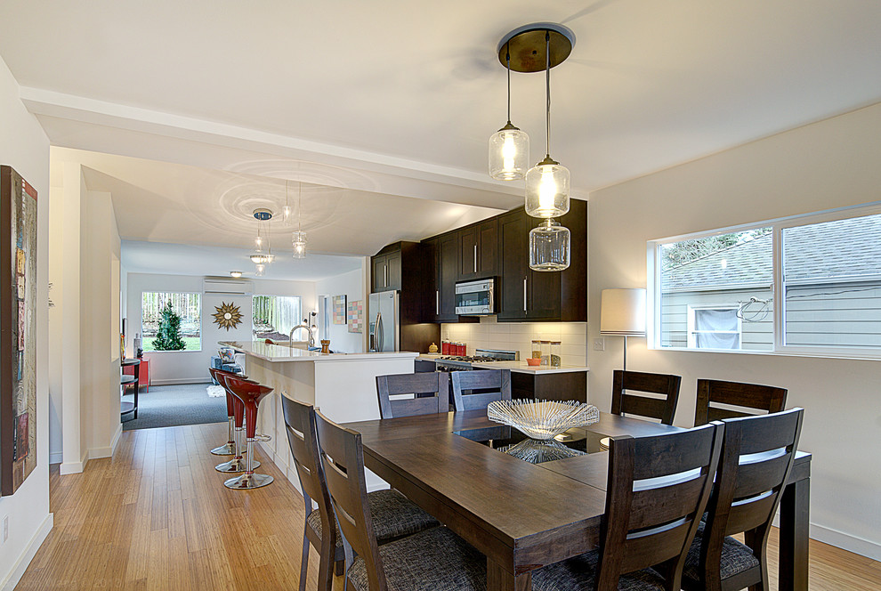Aménagement d'une salle à manger ouverte sur la cuisine classique avec un mur blanc et un sol en bois brun.