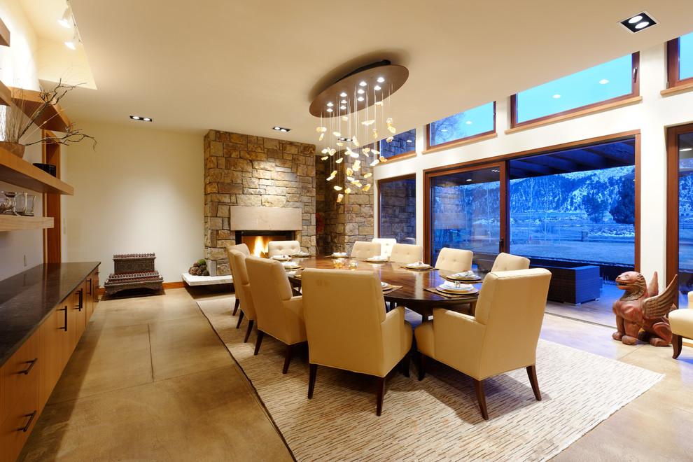 Idée de décoration pour une salle à manger tradition avec un mur beige et un manteau de cheminée en pierre.