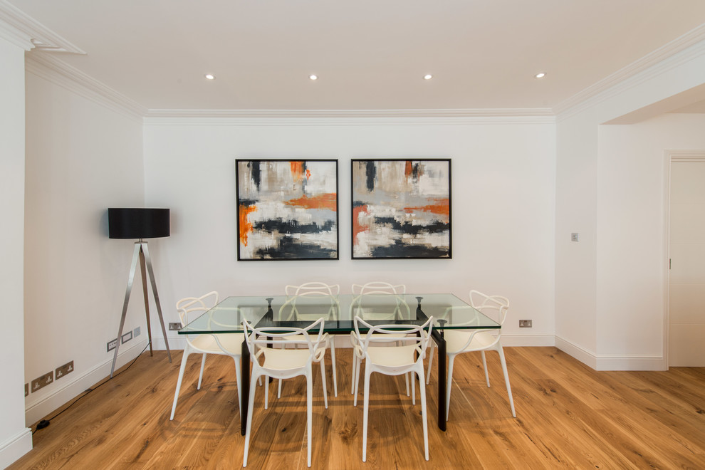 Immagine di una sala da pranzo aperta verso il soggiorno contemporanea con pareti bianche e pavimento in legno massello medio