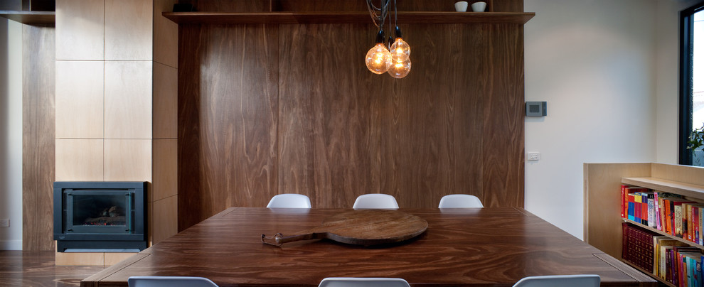 Esempio di una piccola sala da pranzo aperta verso la cucina moderna con pareti bianche, camino classico e cornice del camino in legno