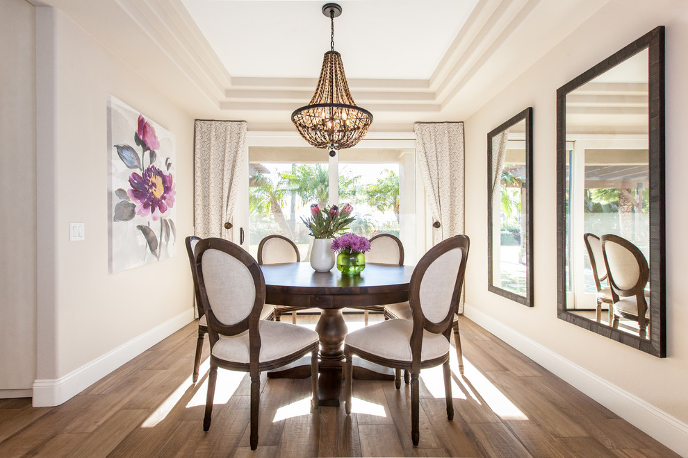 This is an example of a mediterranean dining room in San Diego with beige walls and light hardwood flooring.