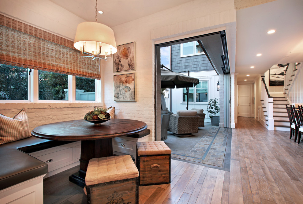 Inspiration pour une salle à manger traditionnelle avec un mur blanc et un sol en bois brun.