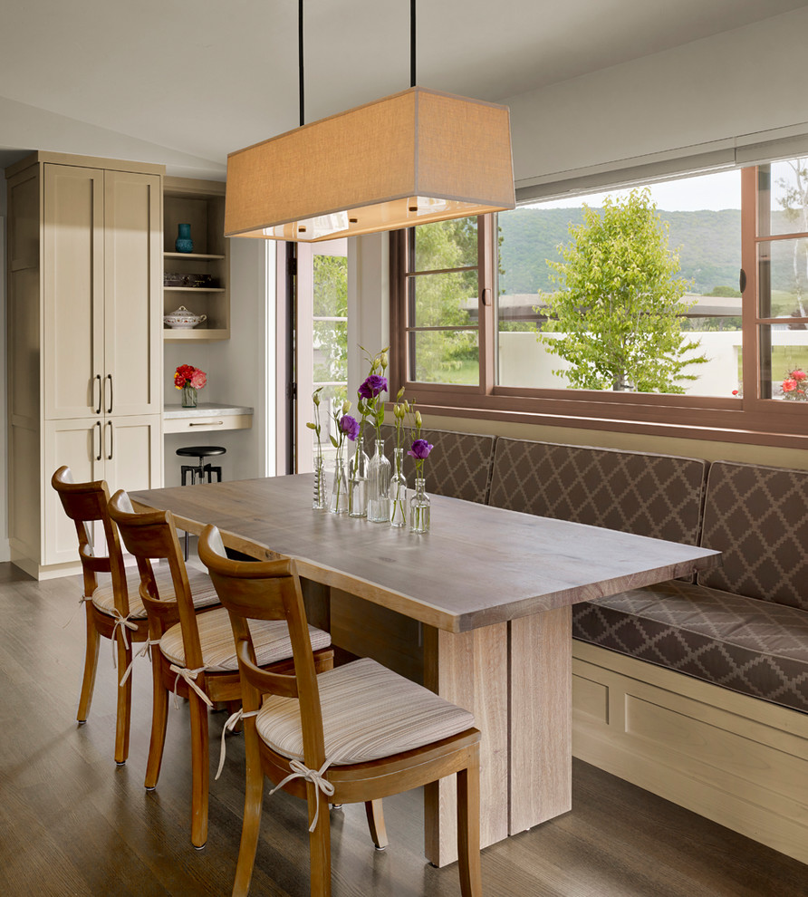 Exemple d'une salle à manger ouverte sur la cuisine chic avec un mur blanc, un sol en bois brun, aucune cheminée et un sol marron.