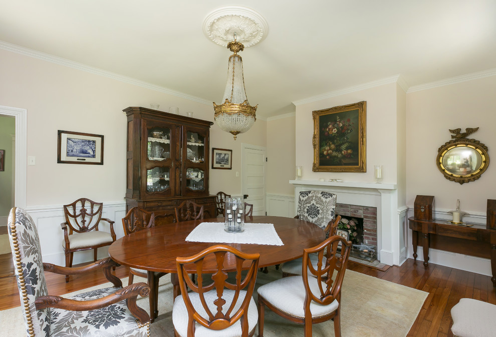 Foto di una sala da pranzo tradizionale chiusa e di medie dimensioni con pareti beige, parquet scuro, camino classico, cornice del camino in mattoni e pavimento marrone