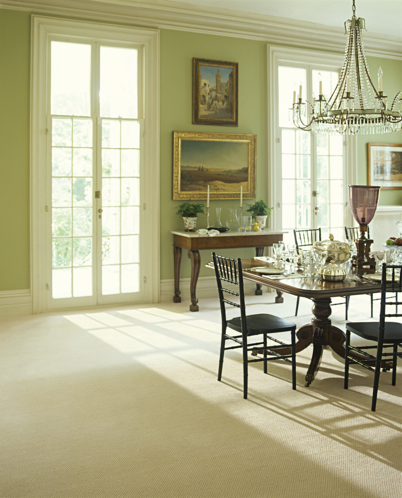 Cette image montre une salle à manger ouverte sur le salon victorienne avec un mur vert et moquette.