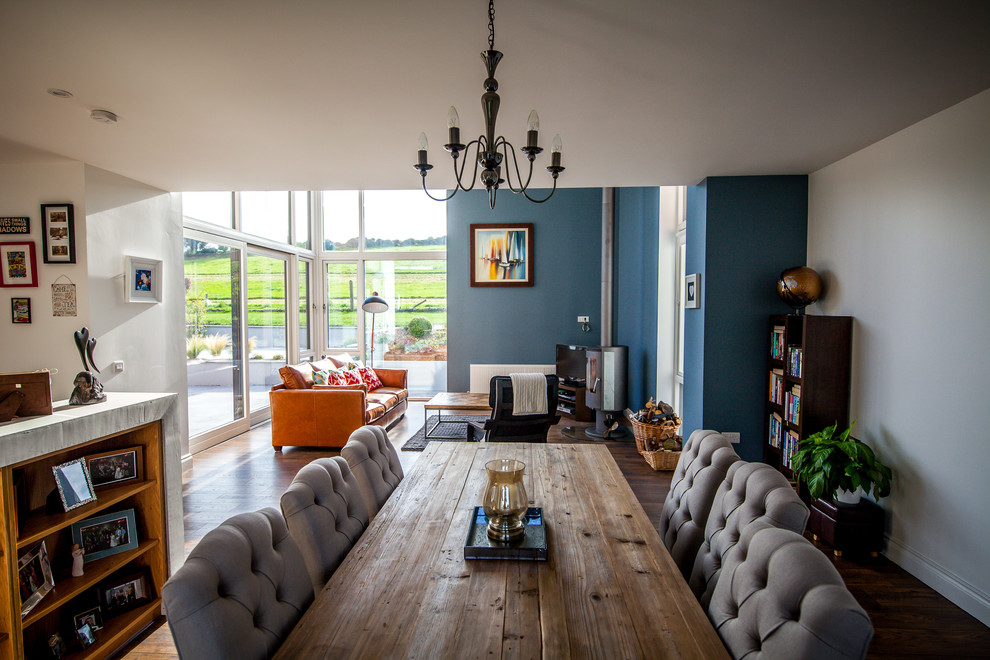 Esempio di una sala da pranzo aperta verso il soggiorno contemporanea con pareti multicolore, parquet scuro e stufa a legna