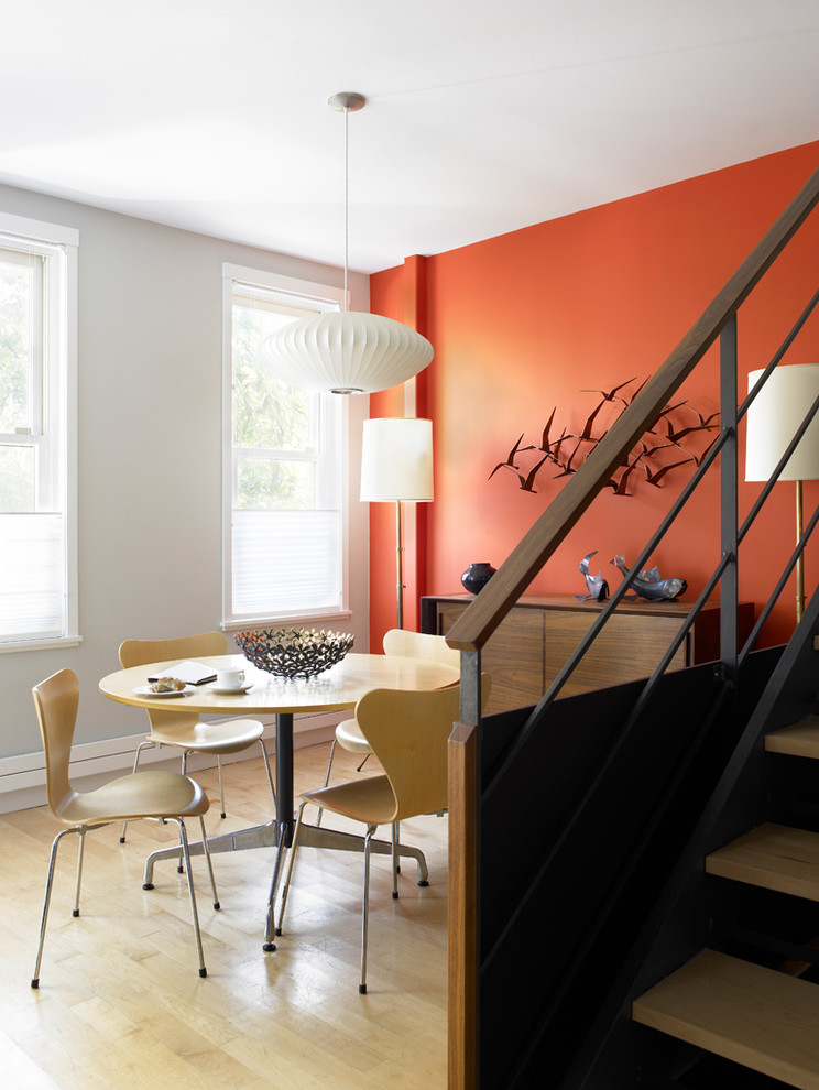 Inspiration for a mid-century modern light wood floor dining room remodel in New York with orange walls