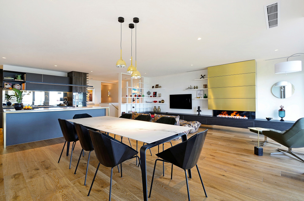 Foto di una sala da pranzo aperta verso il soggiorno contemporanea con pareti bianche, pavimento in legno massello medio e pavimento marrone