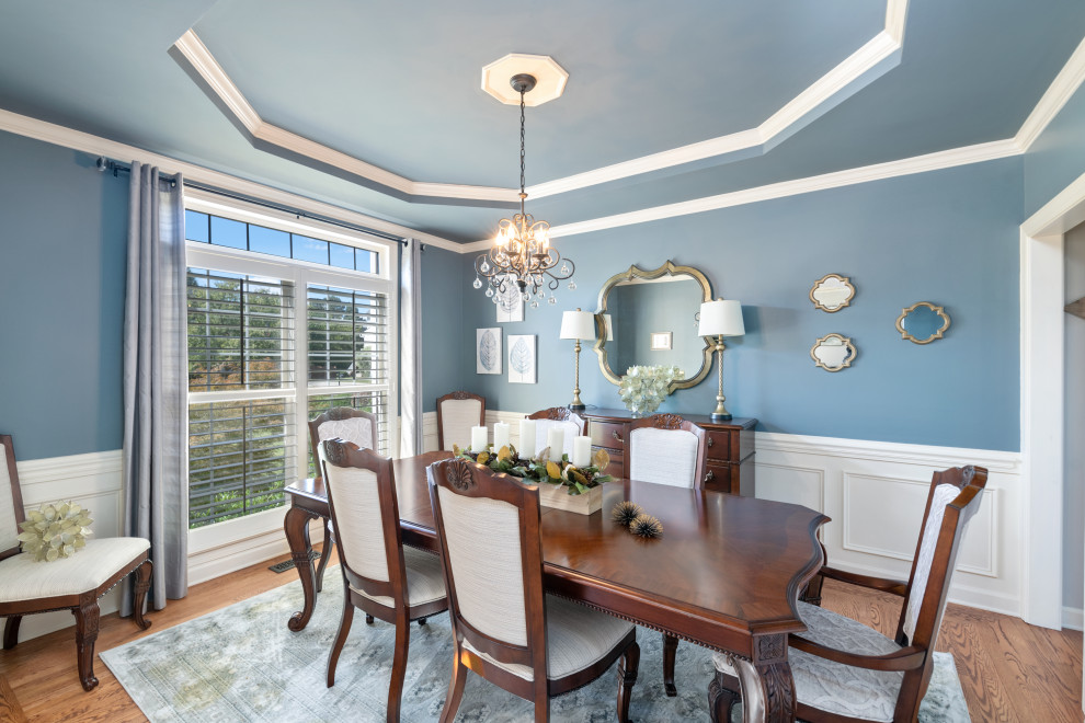Foto di una grande sala da pranzo classica chiusa con pareti blu, pavimento in legno massello medio e pavimento marrone