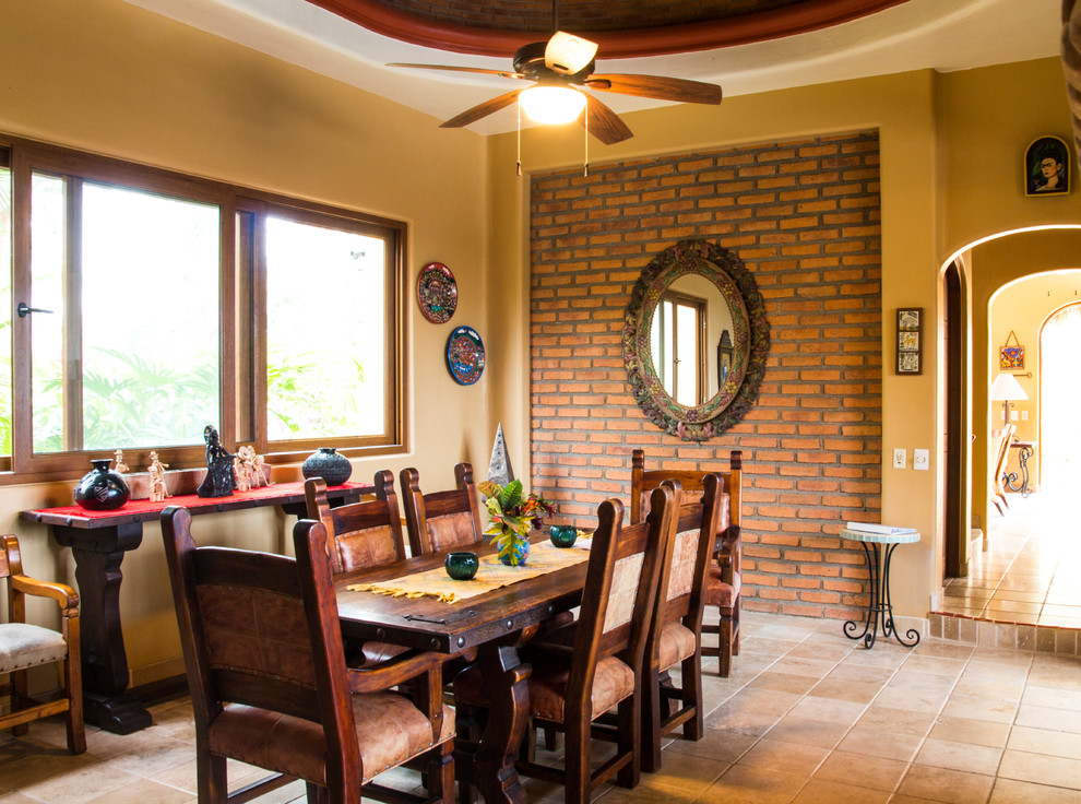 Immagine di una sala da pranzo mediterranea chiusa con pareti gialle, pavimento in terracotta e pavimento rosso