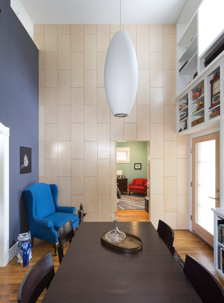 Cette photo montre une petite salle à manger tendance fermée avec un mur bleu et un sol en bois brun.