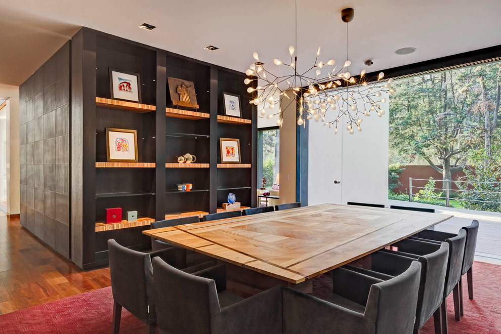 This is an example of a contemporary dining room in Mexico City with white walls and medium hardwood flooring.