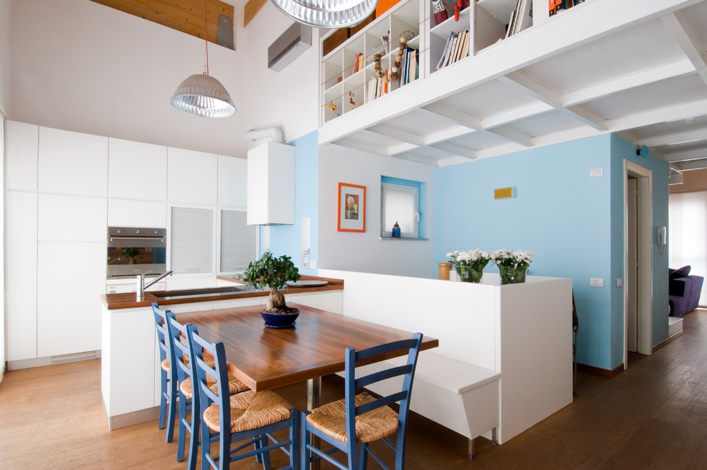 Exemple d'une salle à manger ouverte sur la cuisine éclectique avec un mur bleu et un sol en bois brun.