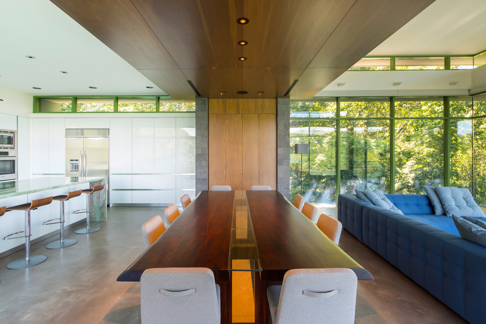 На фото: большая гостиная-столовая в стиле модернизм с белыми стенами, бетонным полом и серым полом без камина с