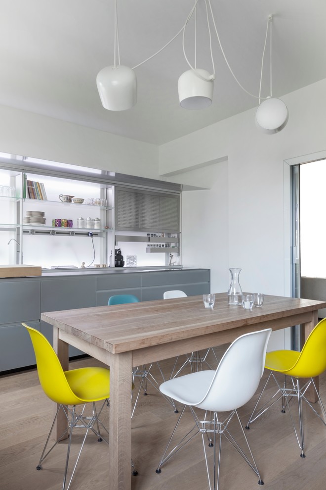 Aménagement d'une salle à manger ouverte sur la cuisine moderne avec un mur blanc et parquet clair.