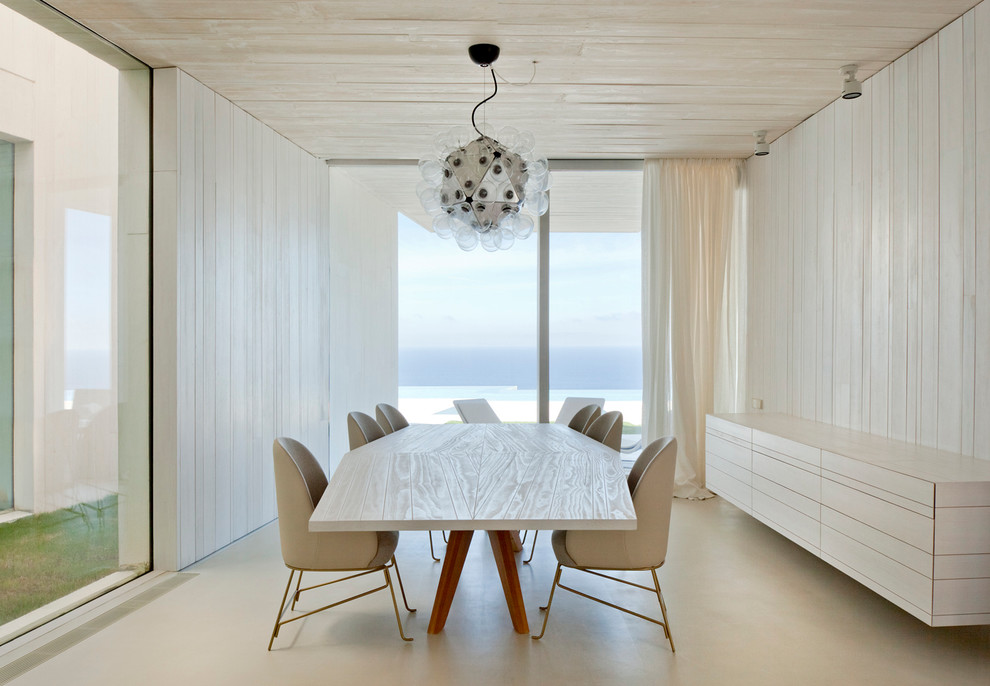 На фото: огромная отдельная столовая в современном стиле с белыми стенами и бетонным полом без камина