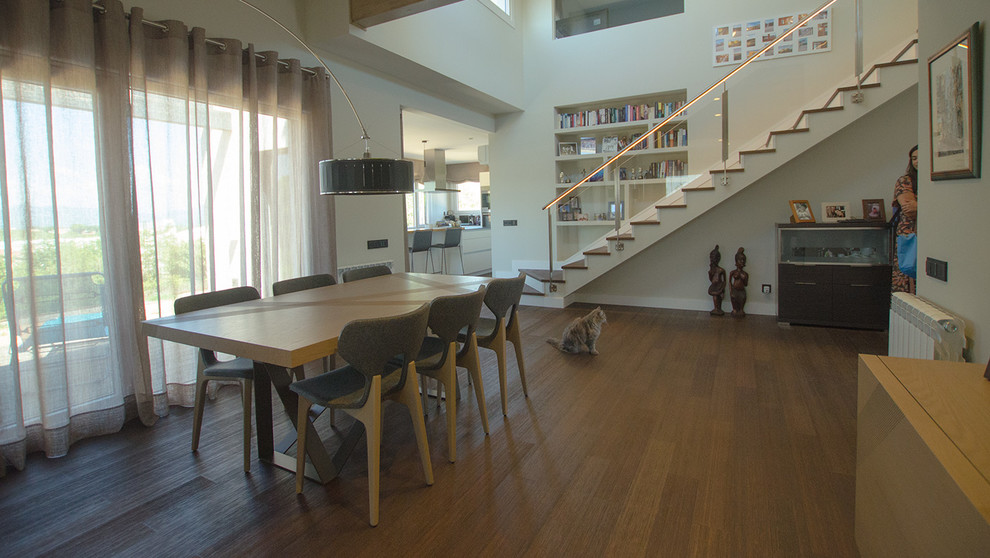 Immagine di una sala da pranzo aperta verso il soggiorno minimalista con pareti beige, pavimento in legno massello medio e pavimento marrone