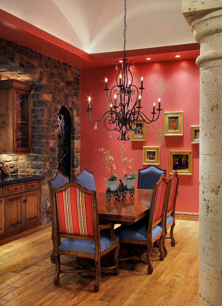 Aménagement d'une salle à manger méditerranéenne avec un mur rouge et un sol en bois brun.