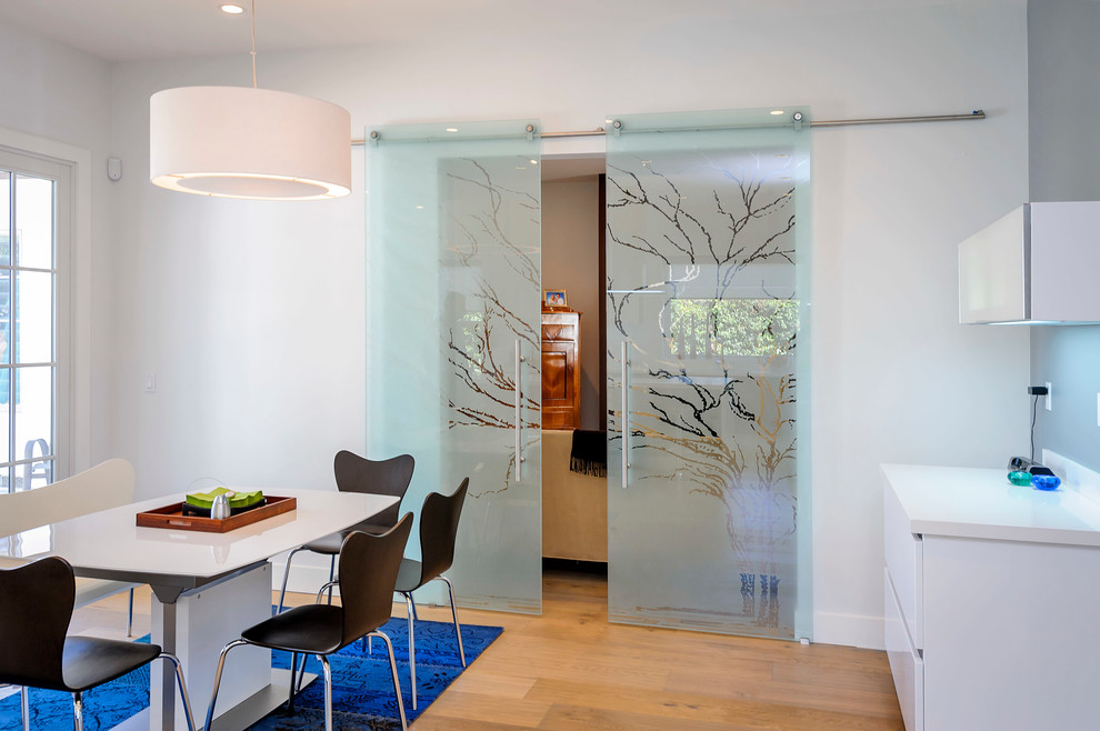 Esempio di una grande sala da pranzo aperta verso la cucina minimalista con pareti bianche e parquet chiaro