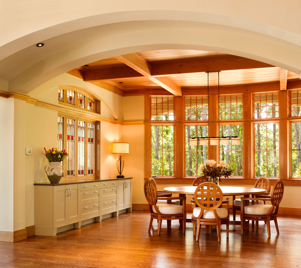 Cette photo montre une salle à manger chic avec un mur beige, un sol en bois brun et éclairage.