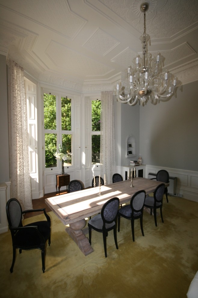 Стильный дизайн: большая гостиная-столовая в викторианском стиле с серыми стенами, ковровым покрытием и печью-буржуйкой - последний тренд