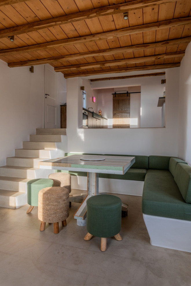Immagine di un angolo colazione mediterraneo con pavimento beige, soffitto in legno, travi a vista e pareti bianche