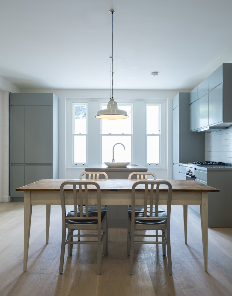 Immagine di una sala da pranzo aperta verso la cucina minimal con pareti bianche e parquet chiaro