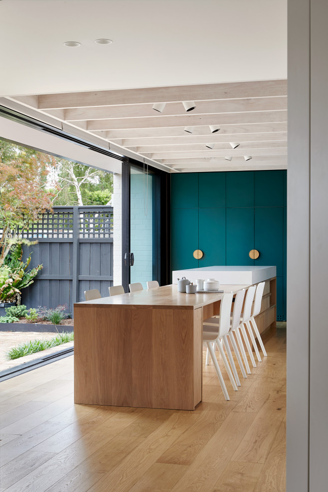 Kleine Moderne Wohnküche mit grüner Wandfarbe, hellem Holzboden und braunem Boden in Melbourne