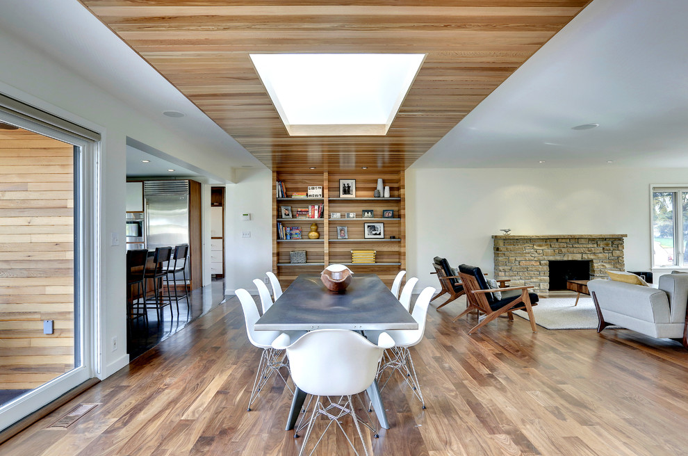 Idee per una sala da pranzo aperta verso il soggiorno moderna con pareti bianche e cornice del camino in pietra