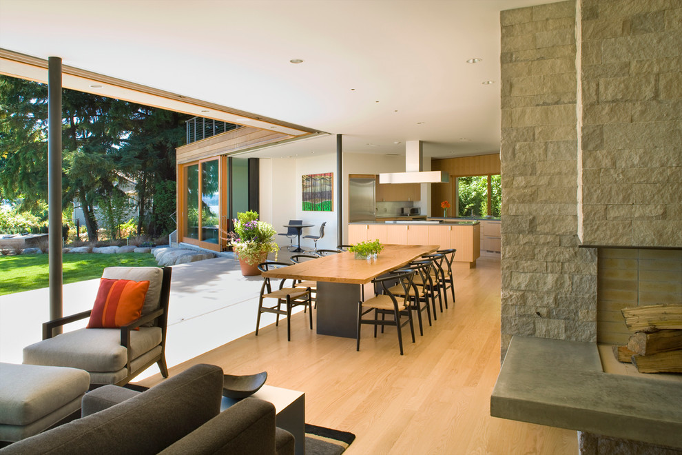 Photo of a large contemporary open plan dining room in Seattle with white walls, light hardwood flooring and a stone fireplace surround.