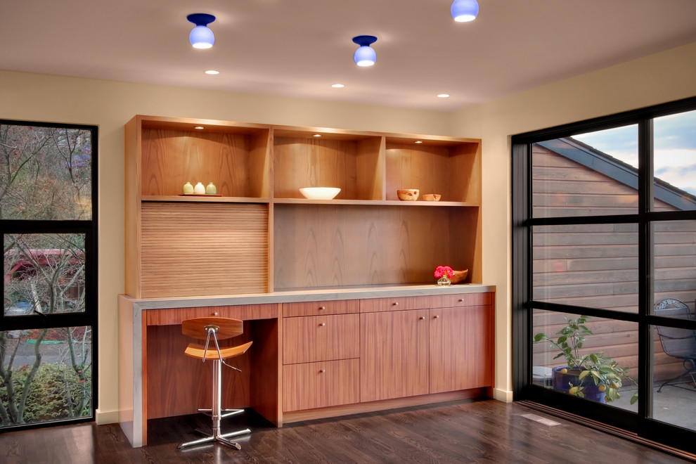 This is an example of a modern dining room in Seattle with beige walls, dark hardwood flooring and feature lighting.