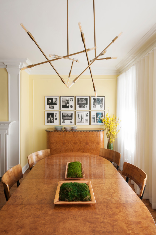 Aménagement d'une salle à manger ouverte sur le salon éclectique de taille moyenne avec un mur jaune, un sol en bois brun, une cheminée standard, un manteau de cheminée en bois et un sol marron.