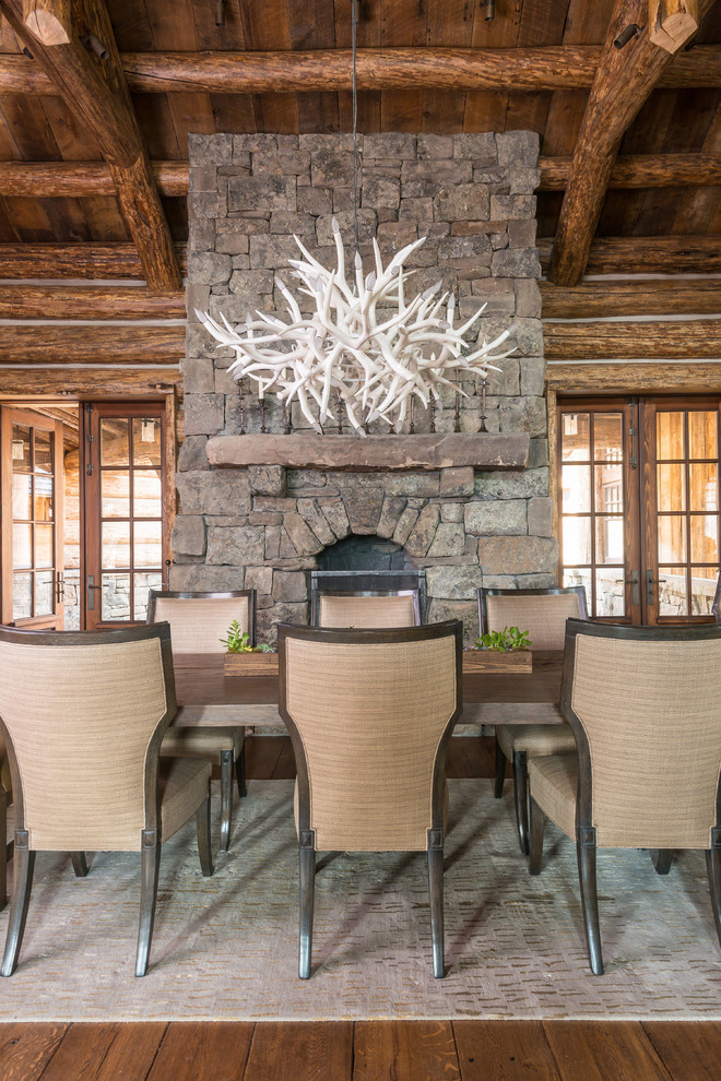 Inspiration pour une salle à manger chalet avec un sol en bois brun, une cheminée standard et un manteau de cheminée en pierre.